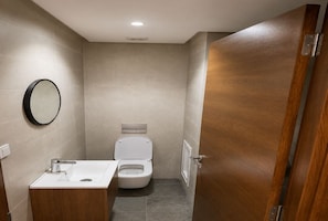 Casa de banho compacta com sanita, lavatório e espelho na parede.