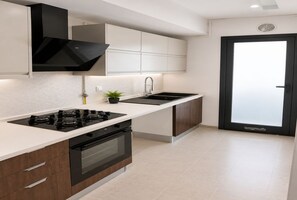 A modern kitchen with a gas stove, oven, and a black range hood. - Peaceful Garden (Tunis)