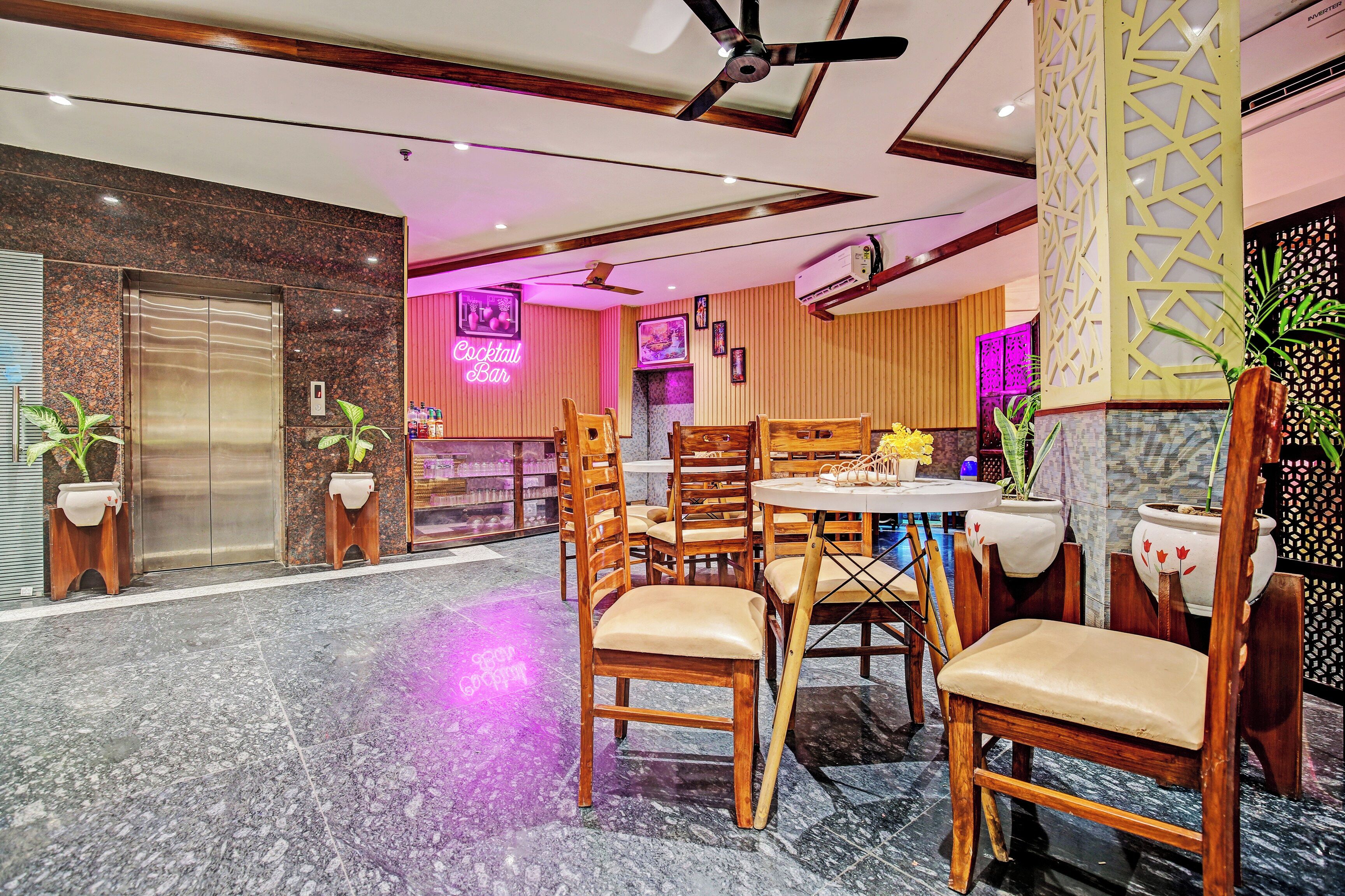 Un vestíbulo de hotel con una mesa de recepción, una zona de bar y espacios de descanso.