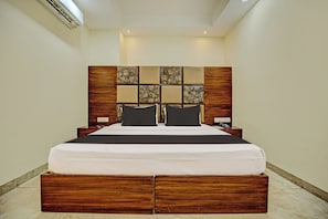 Una habitación de hotel con una cama grande, cabecera de madera y mesita de noche integrada.