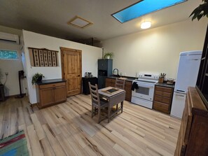 Een keuken met houten kastjes, een eettafel en een inbouwoven.