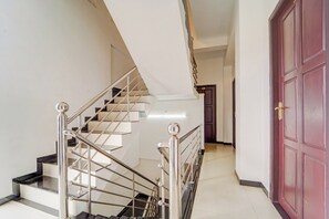 A staircase with metal railings and a red door in the hallway.