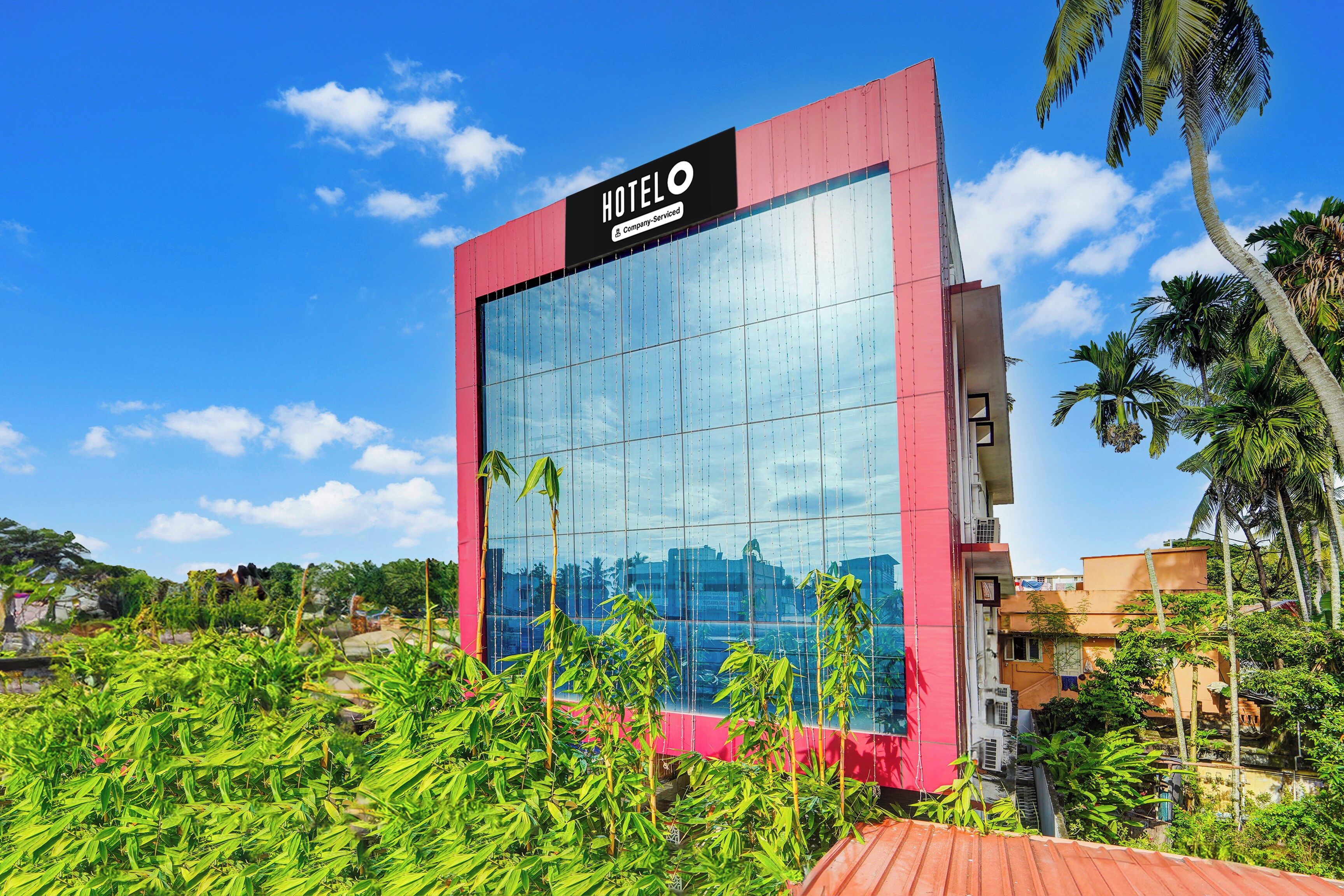 Un edificio moderno de hotel con una amplia fachada de vidrio y un cartel llamativo.