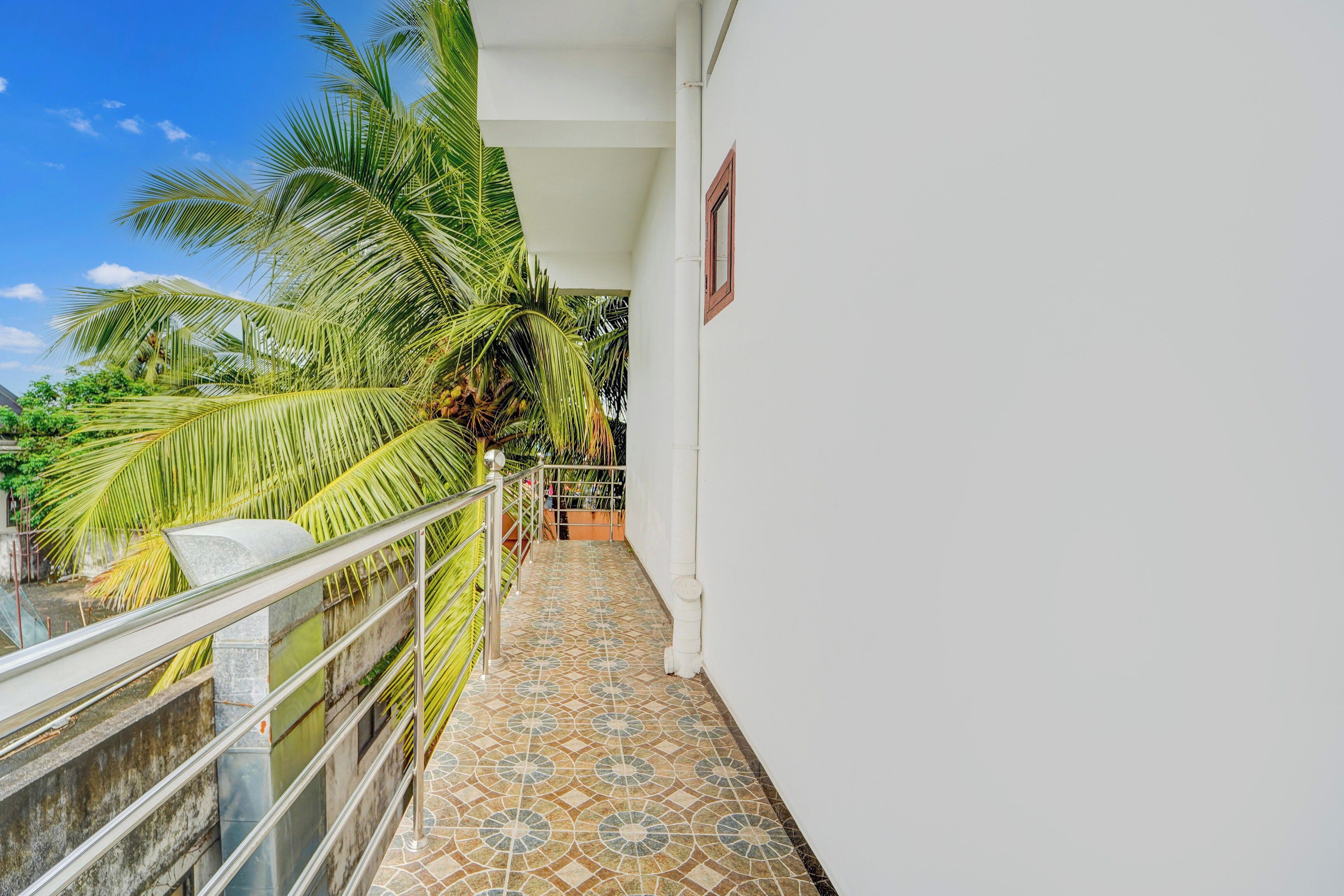 Ein Balkon mit Fliesenboden, Metallgeländer und einer Palme.
