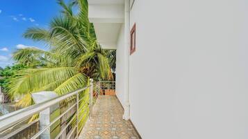 A balcony with a tiled floor, a metal railing, and a palm tree.