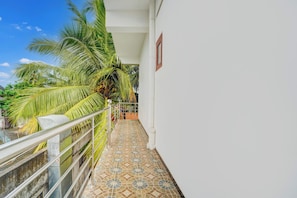 A balcony with a tiled floor, a metal railing, and a palm tree.