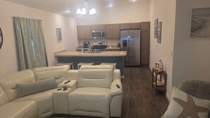 A modern living room with a sofa, a coffee table, and a remote control on the sofa. - Cozy 2-bedroom house in the villages. (Wildwood)