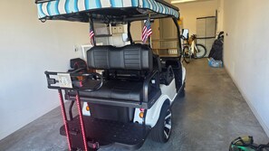 Een golftrolley met een zonnedak, een Amerikaanse vlag en een achteruitkijkspiegel in een garage.