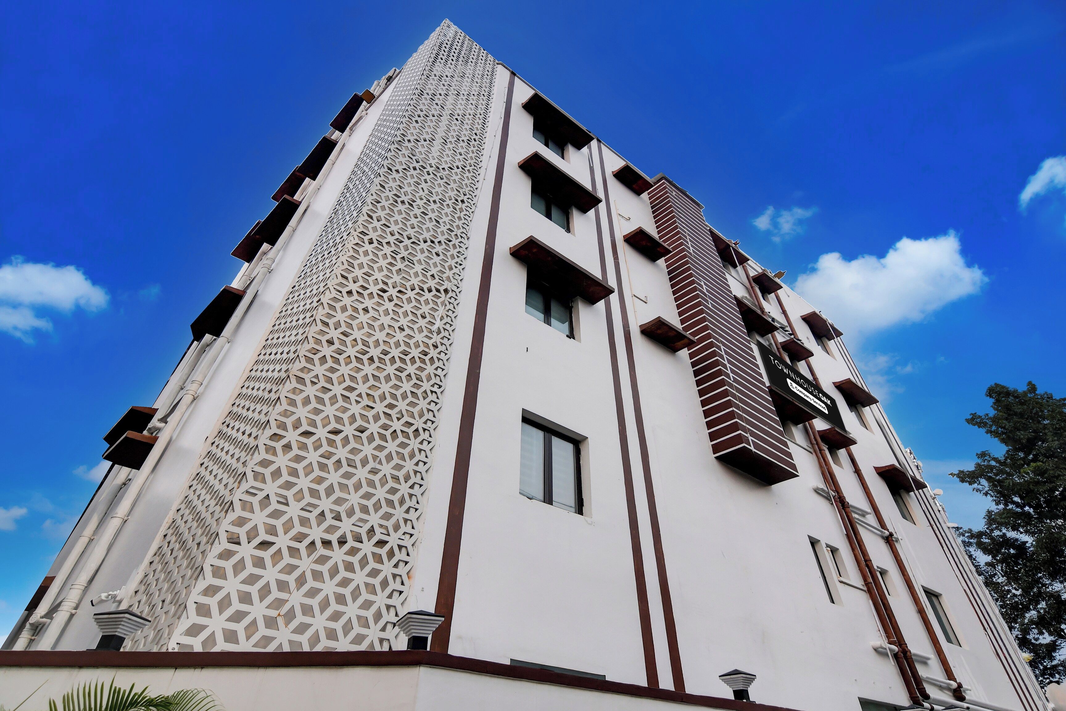 Un immeuble à plusieurs étages doté d’une façade géométrique, d’un élément vertical marquant et d’un ciel d égagé en arrière-plan.
