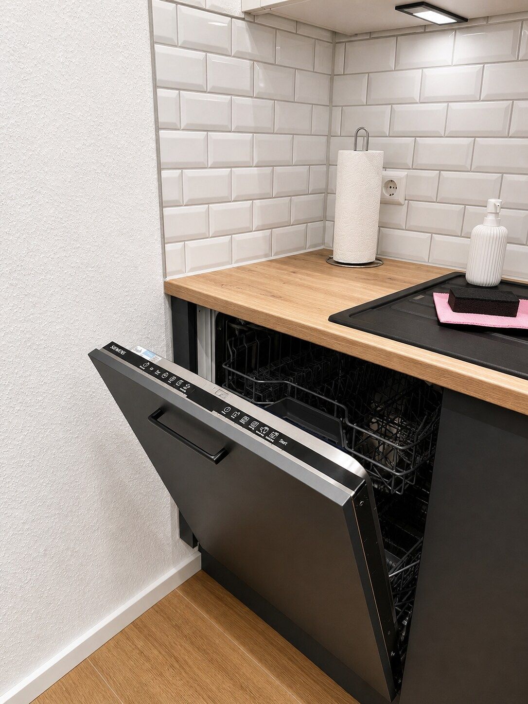 Eine moderne Küche mit Geschirrspüler, einer Arbeitsplatte und einer gefliesten Spritzschutzwand.