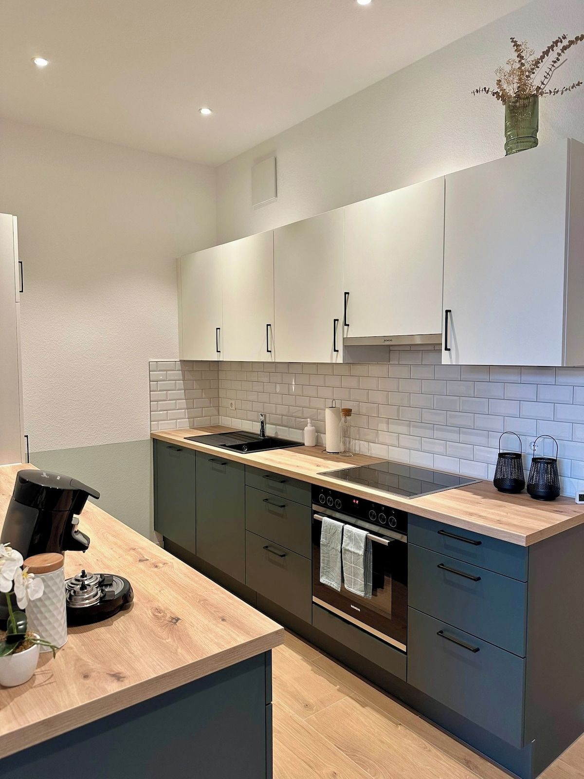 Een moderne keuken met een houten aanrechtblad, roestvrijstalen apparatuur en lichtgekleurde kastjes.