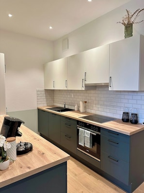 A modern kitchen with a wooden countertop, stainless steel appliances, and light-colored cabinets.
