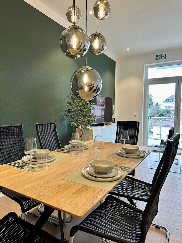 A dining area with a wooden table, black chairs, and a green wall.