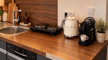 A kitchen with a wooden countertop, a coffee maker, a kettle, and a dishwasher.