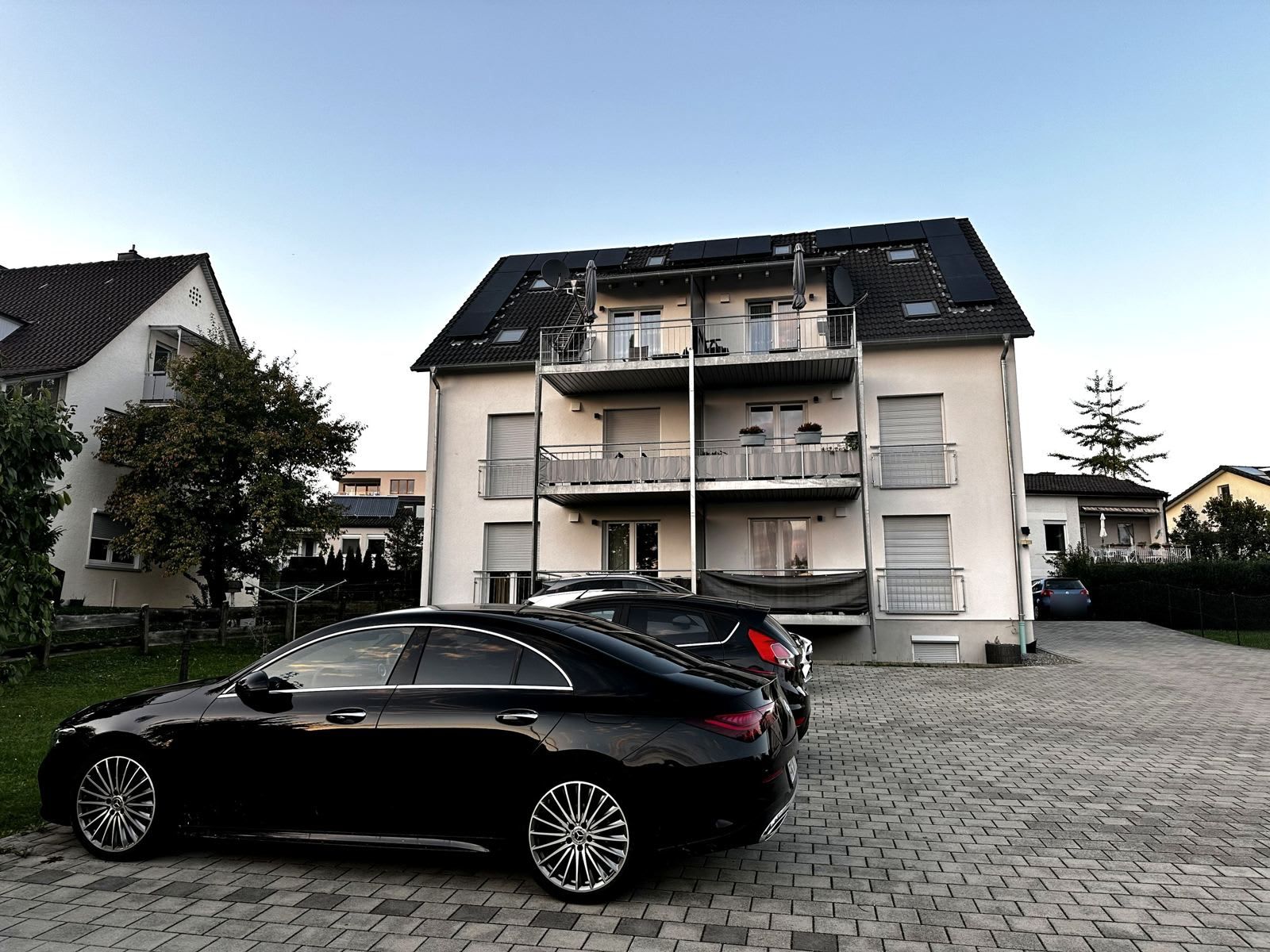 A multi-story residential building with a car parked in front.