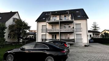 A multi-story residential building with a car parked in front.
