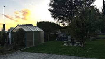 A greenhouse with a metal roof, surrounded by grass and trees.