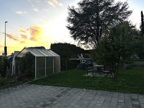 A greenhouse with a metal roof, surrounded by grass and trees. - STAY | Easy Apartment, Parkplatz, Bodensee (Friedrichshafen)