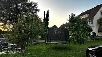 A residential area with a trampoline in a yard, surrounded by trees and a house.