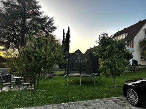 A residential area with a trampoline in a yard, surrounded by trees and a house. - STAY | Easy Apartment, Parkplatz, Bodensee (Friedrichshafen)