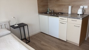 Ett litet, praktiskt kök med en diskho, en kaffebryggare och ett litet bord med en lampa.