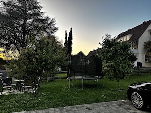 A residential area with a trampoline, trees, and a parked car. - STAY | Smart Studio, Parkplatz, Bodensee (Friedrichshafen)