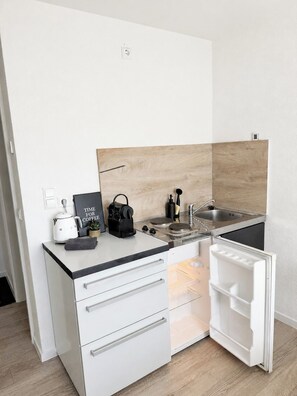 A compact kitchenette with a built-in refrigerator, a stovetop, and a sink. - STAY | Ruhig für 1 · 300 m zum See · Parkplatz (Friedrichshafen)