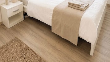 Ein Schlafzimmer mit einem Bett, Nachttischen, einem Beistelltisch und zwei gerahmten Bildern an der Wand.