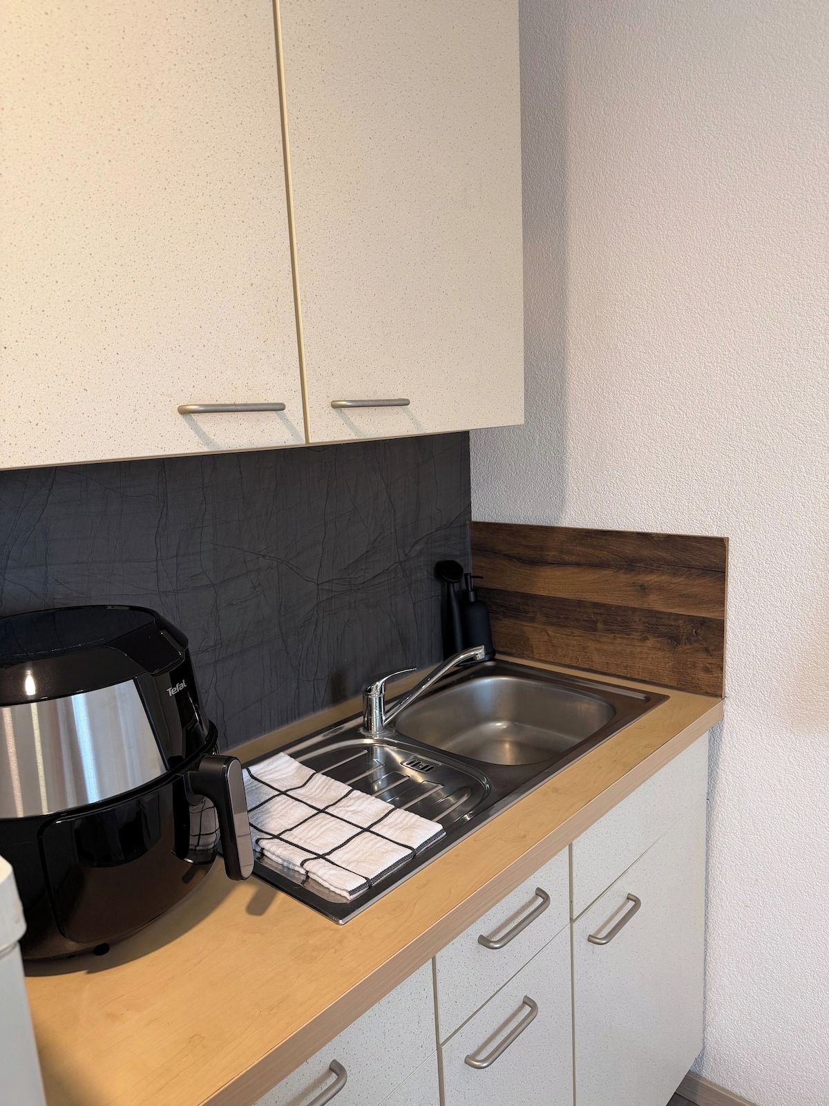 A kitchenette with a coffee maker, a sink, and a countertop with a dish rack.