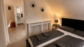 Ein Schlafzimmer mit einem großen Bett, einem Nachttisch mit Lampe und Blick auf ein Badezimmer.