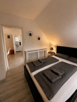 Ein Schlafzimmer mit einem großen Bett, einem Nachttisch mit Lampe und Blick auf ein Badezimmer.