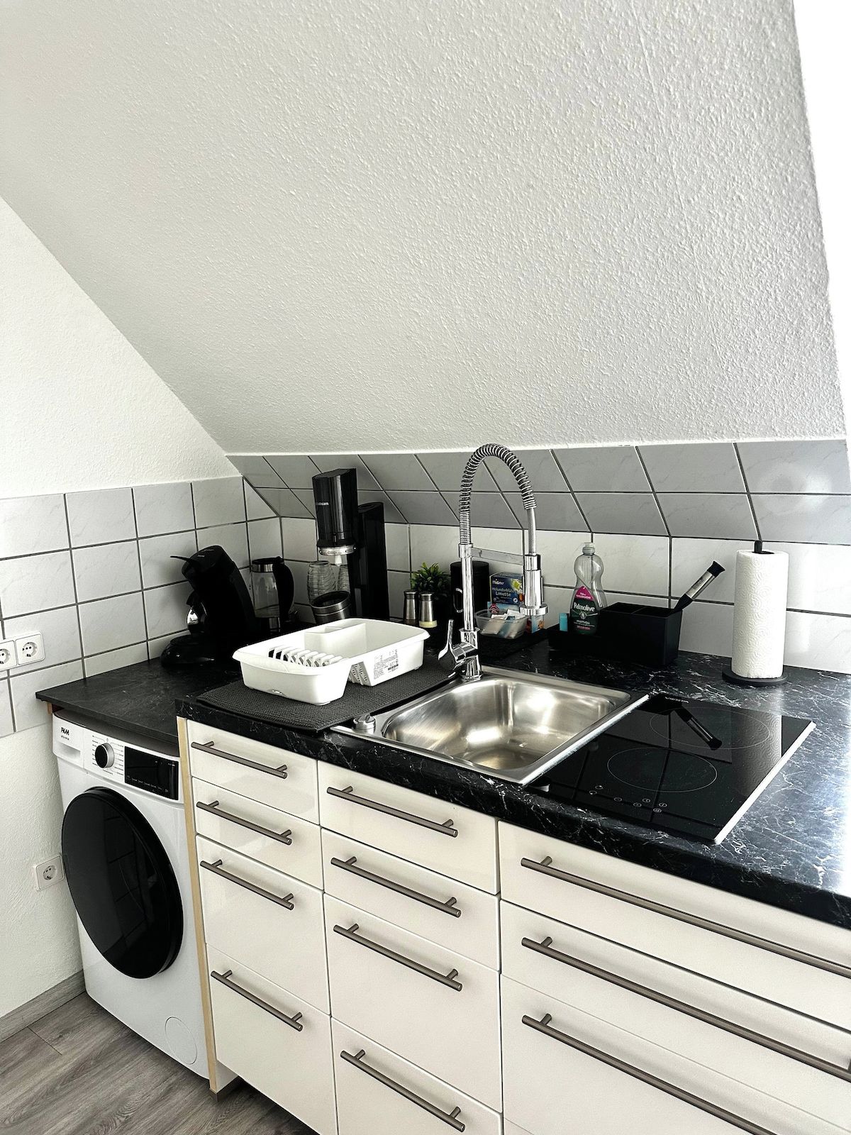 A compact kitchen with a built-in washing machine, a sink, and a stove.