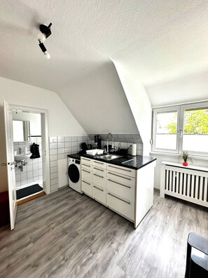 Eine moderne Küche mit Einbauwaschmaschine, Spüle und Fenster mit Blick ins Grüne.
