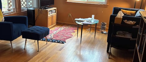 A living room with a television, sofa, and a window with blinds.