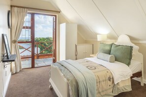 A bedroom with a bed, a nightstand, a lamp, a window with curtains, and a view of the outdoors. - Milkwood Sanctuary, 6-Bed Home in Hermanus (Hermanus)