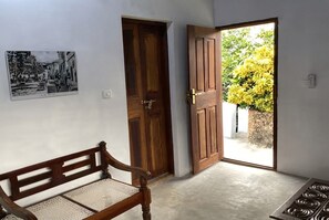 A room with a wooden bench, a door, and a wall-mounted picture.