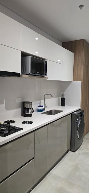 A modern kitchen with a built-in microwave, a coffee maker, and a dishwasher. - New Studio Steps from Santa Marta Marina & Beach - A/C, Washer-Dryer (Santa Marta)
