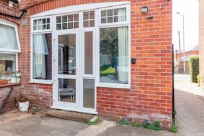 A red brick house with a bay window, a white door, and a small garden area. - Private Studio Near Shops & River Thames - Pass the Keys (Reading)