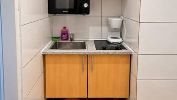 A compact kitchen with a microwave, coffee maker, and a sink.