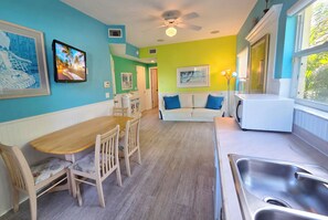 A kitchen with a dining area, a white refrigerator, a sink, and a ceiling fan. - Resort Style, Walk to Beach & Village, Heated Pool, Tiki (Siesta Key)