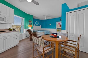 A kitchen with white cabinets, a dining table with chairs, and a blue accent wall. - Short Walk to Beach & Village, Resort Feel, Heated Pool (Siesta Key)