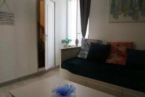 Ein Wohnzimmer mit Sofa, Couchtisch, Treppe und einem Fenster mit Vorhängen.