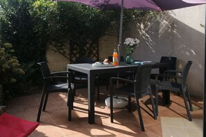 An outdoor patio with a table, chairs, a purple umbrella, and a vase with flowers. - Fleur de Breizh by Archipel Evasion (Cancale)
