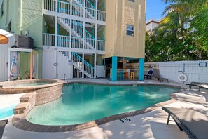 A swimming pool with a hot tub, a covered seating area, and a staircase leading to an upper level. - Sand & Sunsets Steps Away, Heated Pool, Village (Siesta Key)