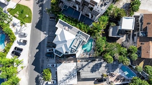 An aerial view of a hotel with multiple swimming pools, a parking lot, and surrounding greenery. - Sand & Sunsets Steps Away, Heated Pool, Village (Siesta Key)