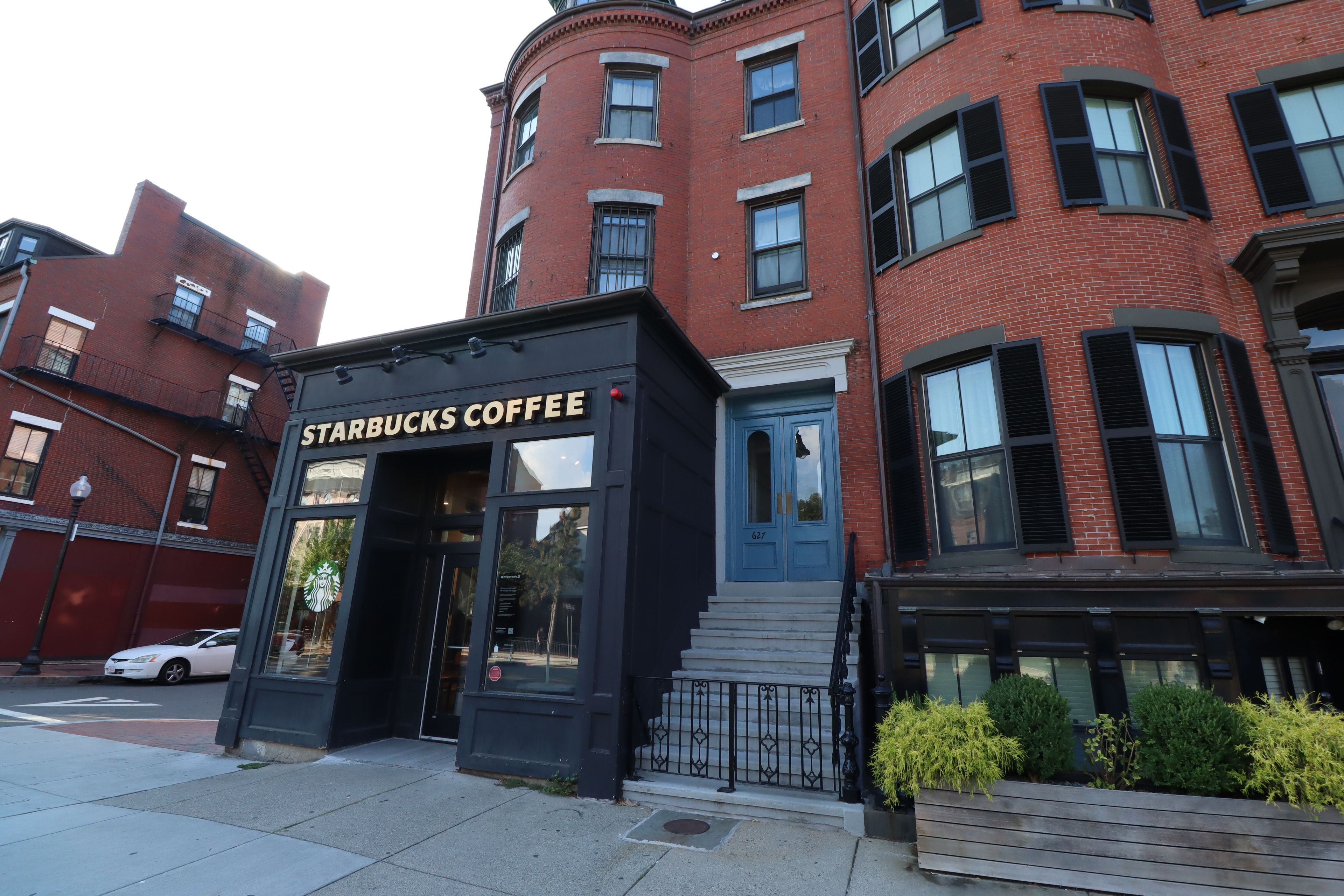 A Starbucks Coffee storefront with a black facade, large windows, and a blue door.