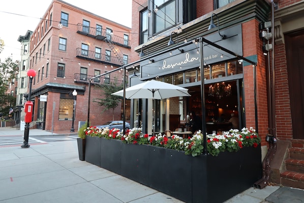 A restaurant with outdoor seating, a brick facade, and a sign reading 'Desnud.' - Good Hotels Boston (Boston)