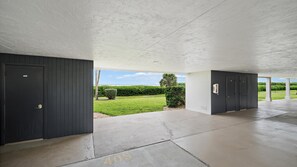 A covered outdoor area with a concrete floor, two doors, and a view of a green landscape. - Heated Pool, Bayfront, Fitness Center, Tennis (Longboat Key)