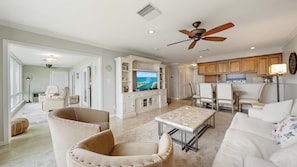 A spacious living area with a large television, inviting seating, and an adjoining dining space. Cream upholstery and soft neutral finishes keep the room bright, comfortable, and easy to enjoy. - Heated Pool, Bayfront, Fitness Center, Tennis (Longboat Key)