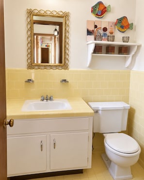 A bathroom with a sink, toilet, and a mirror with an ornate frame. - Fabulous 2-bedroom cabin with AC in charming Talladega (Talladega)